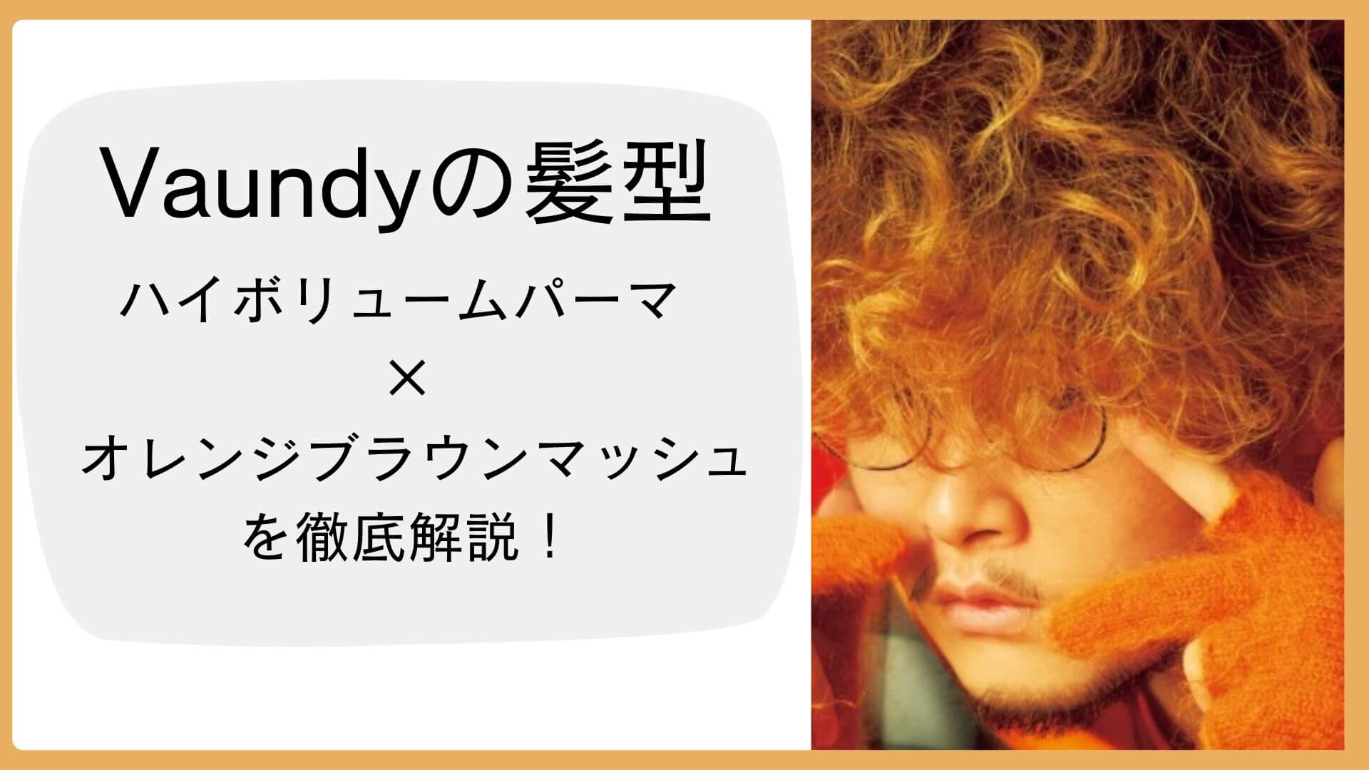 強めのカールが印象的なVaundyのハイボリュームパーマ。オレンジの背景とニットに囲まれたビジュアルで、髪型「オレンジブラウンマッシュ」を表現。