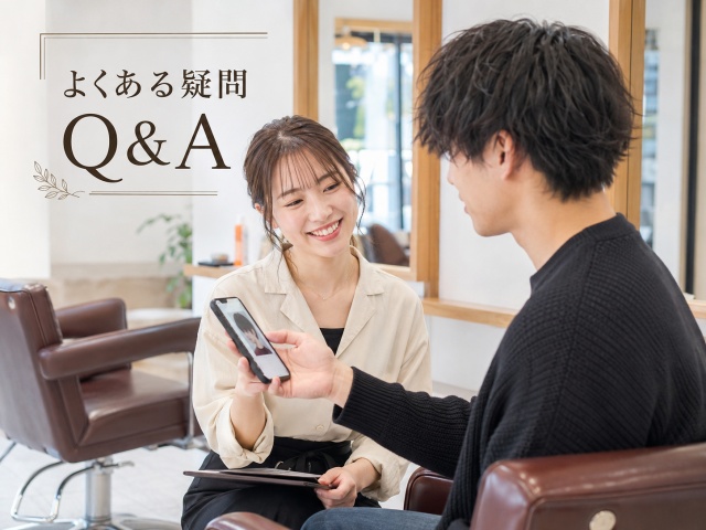 美容室でスマートフォンを見せながら美容師に質問・相談しているイメージ